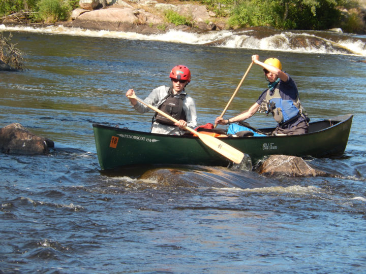 Boys rowing in a canoe on a river
