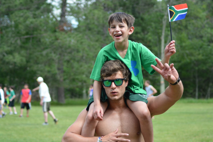 Boys camp councilor with summer camper on his shoulders