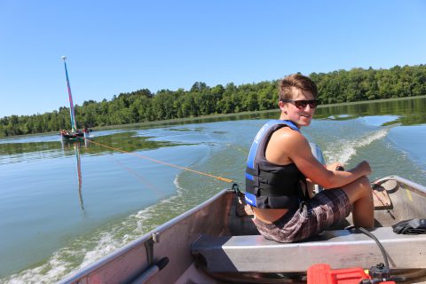 Camp Thunderbird boys camp councilor towing campers around a lake behind a boat