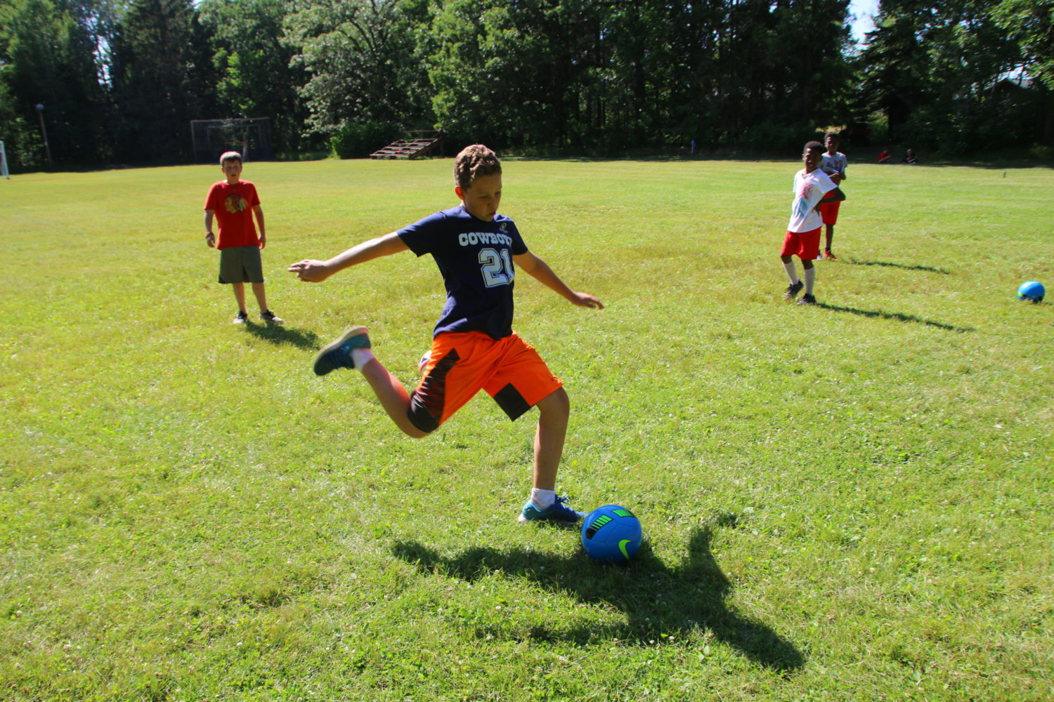 Boy kicking a soccer ball at boys summer camp