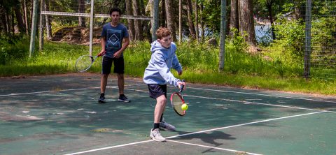 Boy playing tennis at Camp Thunderbird