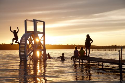 Kids jumping into the lake during summer camp